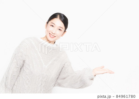 白い背景の前に立って案内をするセーターを着ている主婦 84961780
