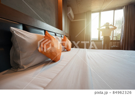 Tourist woman standing nearly window in hotel bedroom after check-in and looking to beautiful view outside window. Conceptual of travel and accommodation. 84962326