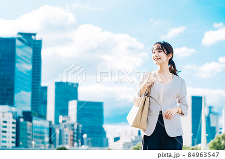 青空とビル群を背景にしたビジネスウーマン 84963547