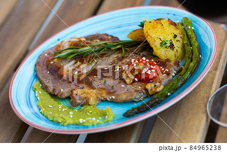 Grilled veal loin with guacamole and vegetables on wooden background 84965238