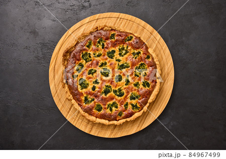 Homemade quiche pie with broccoli, tuna and cheese on round wooden cutting board Homemade quiche pie with broccoli, tuna and cheese on round wooden cutting board 84967499