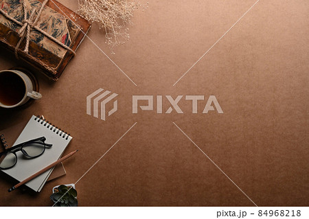 Top view notebook, glasses, coffee cup and vintage books on brown background. 84968218