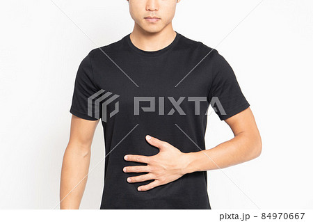 白い背景の前に立って、お腹に手を当てる黒いTシャツを着ている男性 84970667
