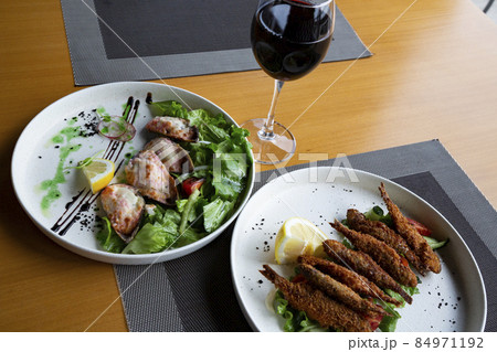 top view, a glass of red wine on the table, mussels and fried fish. Mediterranean cuisine on the table. top view, a glass of red wine on the table, mussels and fried fish. Mediterranean cuisine on the table. 84971192