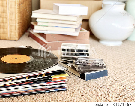 積み上げたレコードジャケットとレコード盤と本と壺など 84971568