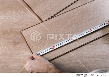 Installing laminate flooring in a room or office. Wooden parquet boards in the hands of a worker. Construction and decorative works for the finishing of housing Installing laminate flooring in a room or office. Wooden parquet boards in the hands of a worker. Construction and decorative works for the finishing of housing 84972775