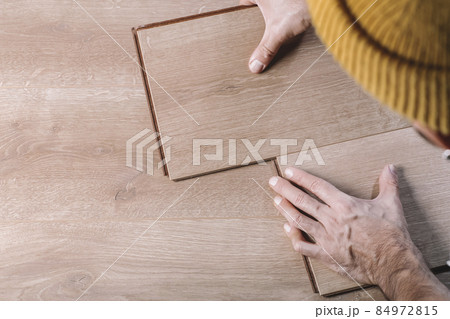 Installing laminate flooring in a room or office. Wooden parquet boards in the hands of a worker. Construction and decorative works for the finishing of housing 84972815