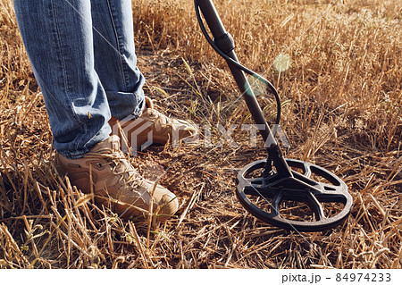 Man with metal detector equipment searching for metal goods in the field Man with metal detector equipment searching for metal goods in the field 84974233