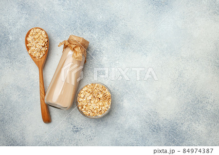 Non dairy oat milk and oat flakes in bowl 84974387