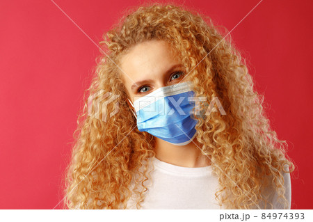 Beautiful young lady with curly hair wearing medical face mask Beautiful young lady with curly hair wearing medical face mask 84974393