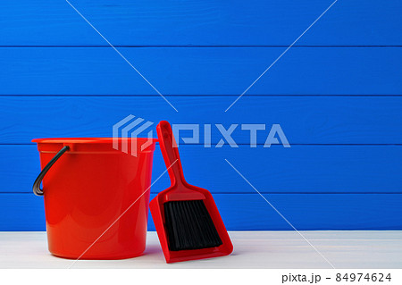 Red plastic bucket and scoop against blue wooden background Red plastic bucket and scoop against blue wooden background 84974624