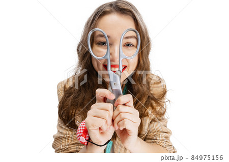 Close-up portrait of smiling young girl, dressmaker posing with scissors isolated on white background. Concept of job, hobby Close-up portrait of smiling young girl, dressmaker posing with scissors isolated on white background. Concept of job, hobby 84975156