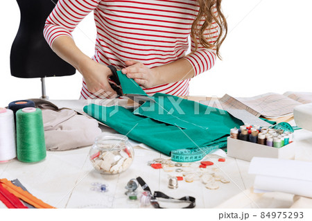 Close-up hands of female seamstress, dressmaker cutting fabric isolated on white background. Concept of job, hobby 84975293