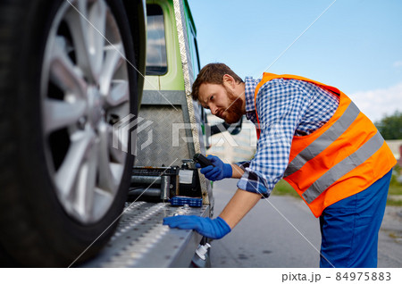 Tow truck operator fixing the car on platform Tow truck operator fixing the car on platform 84975883