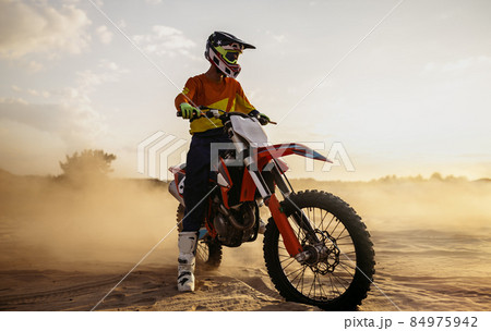 Motocross rider on sportmotor over dust landscape 84975942