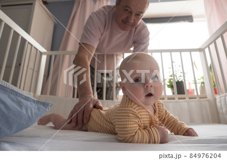 Cheerful senior grandfather playing with grandson at the bedroom Cheerful senior grandfather playing with grandson at the bedroom 84976204