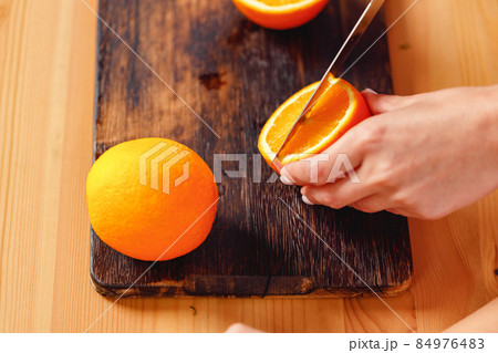 Close up of female hands cutting orange Close up of female hands cutting orange 84976483