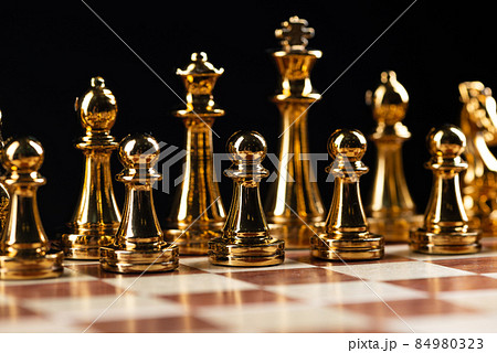 Golden chess figures standing on chessboard Golden chess figures standing on chessboard 84980323