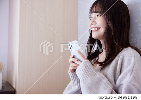ベッドでくつろぎながらスマホを見る女性 84981198