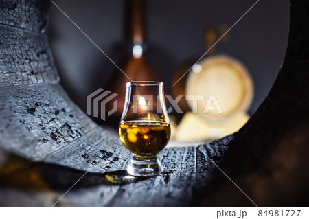 A glass of whiskey in oak barrel A glass of whiskey in oak barrel 84981727