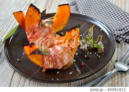 Hokkaido pumpkin gaps wrapped in bacon with sage leaves and thyme, baked in olive oil Hokkaido pumpkin gaps wrapped in bacon with sage leaves and thyme, baked in olive oil 84981813