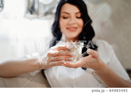 focus on the mug. happy brunette bride drinks tea the morning before the wedding 84983493