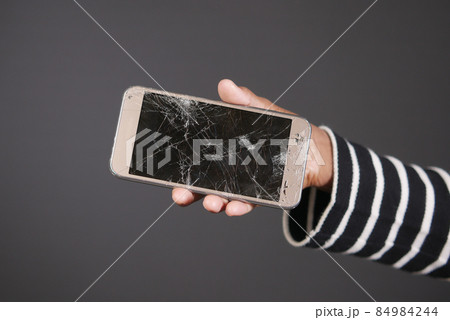 Close up of man hand holding broken smart phone. 84984244