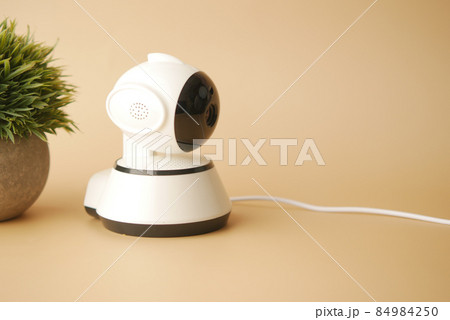 CCTV security camera operating on light orange background  84984250