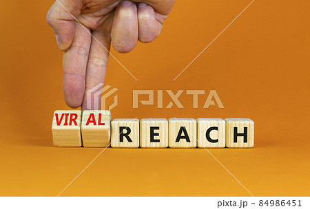 Viral reach symbol. Businessman turns wooden cubes and changes words 'reach' to 'viral reach'. Beautiful orange table, orange background, copy space. Business, viral reach concept. Viral reach symbol. Businessman turns wooden cubes and changes words 'reach' to 'viral reach'. Beautiful orange table, orange background, copy space. Business, viral reach concept. 84986451