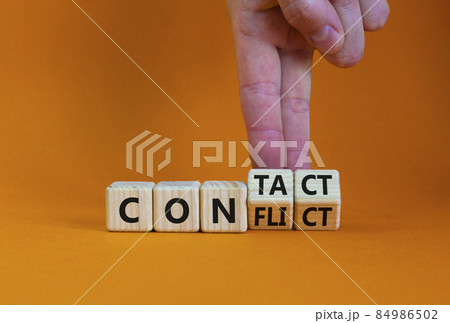 Conflict or contact symbol. Businessman turns wooden cubes and changes the word 'conflict' to 'contact'. Beautiful orange table, orange background, copy space. Business, conflict or contact concept. 84986502