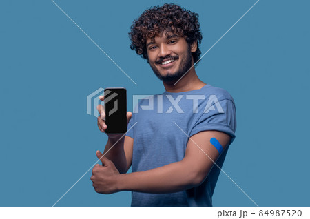 Vaccinated guy with a smartphone making a thumbs-up gesture 84987520