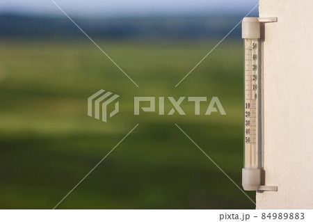 Thermometer celsius showing warm temperature on blurred green ba Thermometer celsius showing warm temperature on blurred green ba 84989883