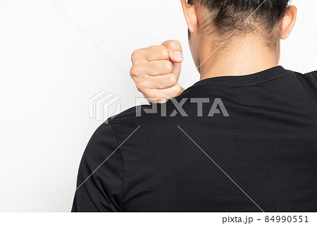 白い背景の前に立って、肩を触る黒いTシャツを着ている若い男性 84990551