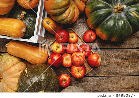 Pumpkins and red apples on wooden background Pumpkins and red apples on wooden background 84990877
