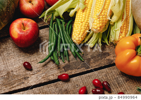 Corn cobs, apples, and pepper on wooden table 84990964
