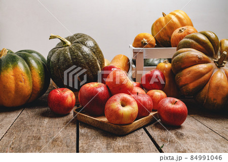 Pumpkins and red apples on wooden background 84991046