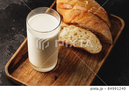 Glass of milk with sliced baguette on wooden board 84991240