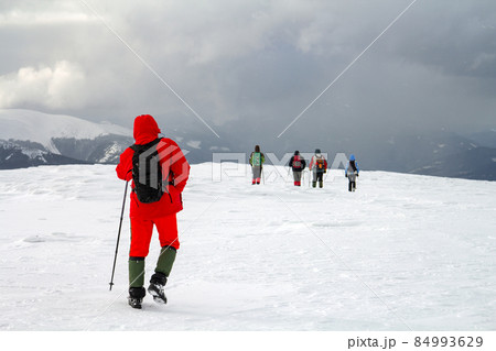 Back view of hikers walking on snow covered hill in winter mountains. 84993629