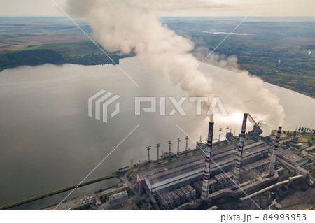 Aerial view of high chimney pipes with grey smoke from coal power plant. Production of electricity with fossil fuel. Aerial view of high chimney pipes with grey smoke from coal power plant. Production of electricity with fossil fuel. 84993953