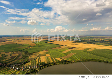 Aerial rural landscape with yellow patched agriculture fields and blue sky with white clouds. 84994022