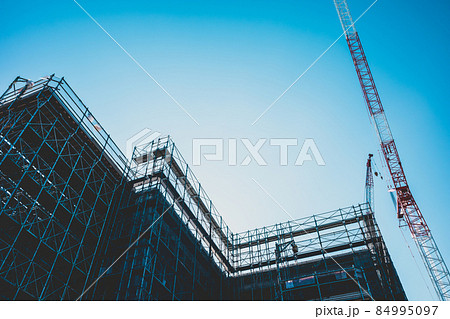 大規模ビル建設工事現場  建築物のシルエットとクレーンと青い空　c-4 マット感 84995097