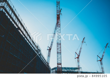 大規模ビル建設工事現場  建築物のシルエットとクレーンと青い空　d-4 マット感 84995105