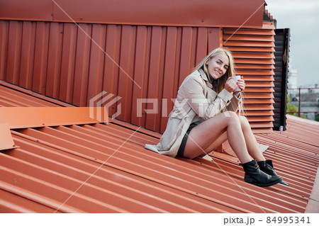 a beautiful woman looks at the city from the roof of the house a beautiful woman looks at the city from the roof of the house 84995341