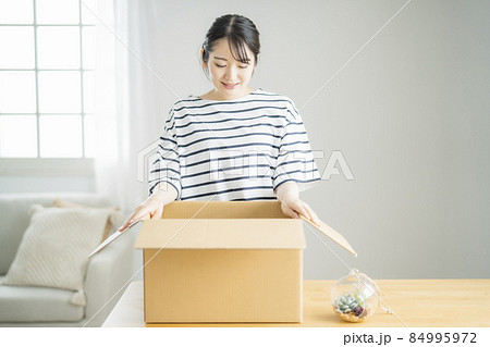 段ボールを開ける女性（笑顔） 84995972