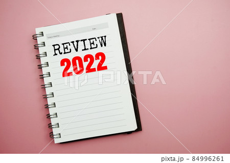 Review 2022 text on paper notebook top view on pink background 84996261