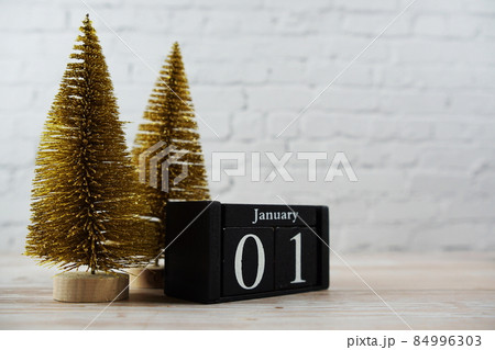January 1st on the wooden calendar with little christmas tree on white brick wall background 84996303