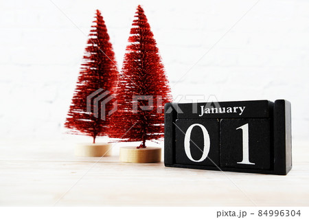 January 1st on the wooden calendar with little christmas tree on white brick wall background 84996304