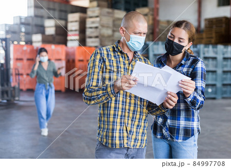 Man and young woman in masks talking about documentation Man and young woman in masks talking about documentation 84997708