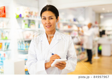 Female pharmacist standing and writing recipe Female pharmacist standing and writing recipe 84997967