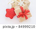 Christmas and New Years decorated gifts. Gift box wrapped in kraft paper with red ribbon. Red knitted heart. Box with jute cord and crocheted snowflake 84999210